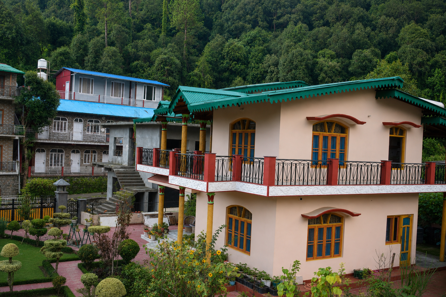 The finished hillside home with painted facade, balcony and landscaped garden
